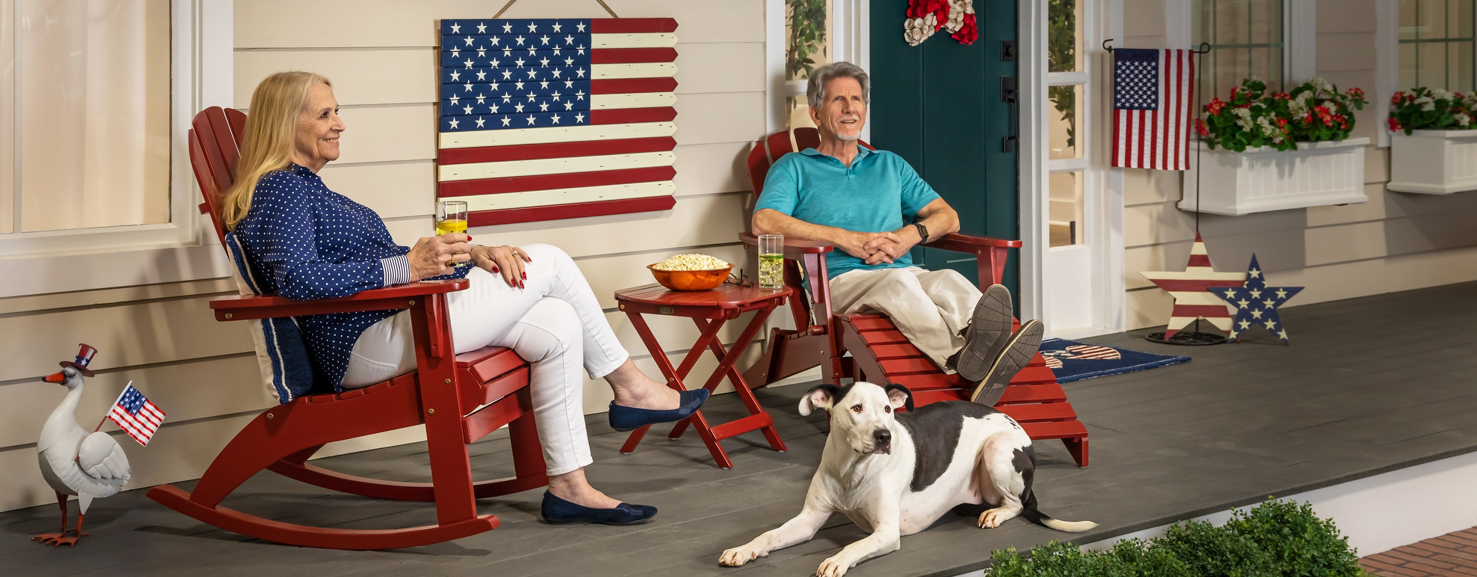 people sitting in adirondack chairs on patriotic porch