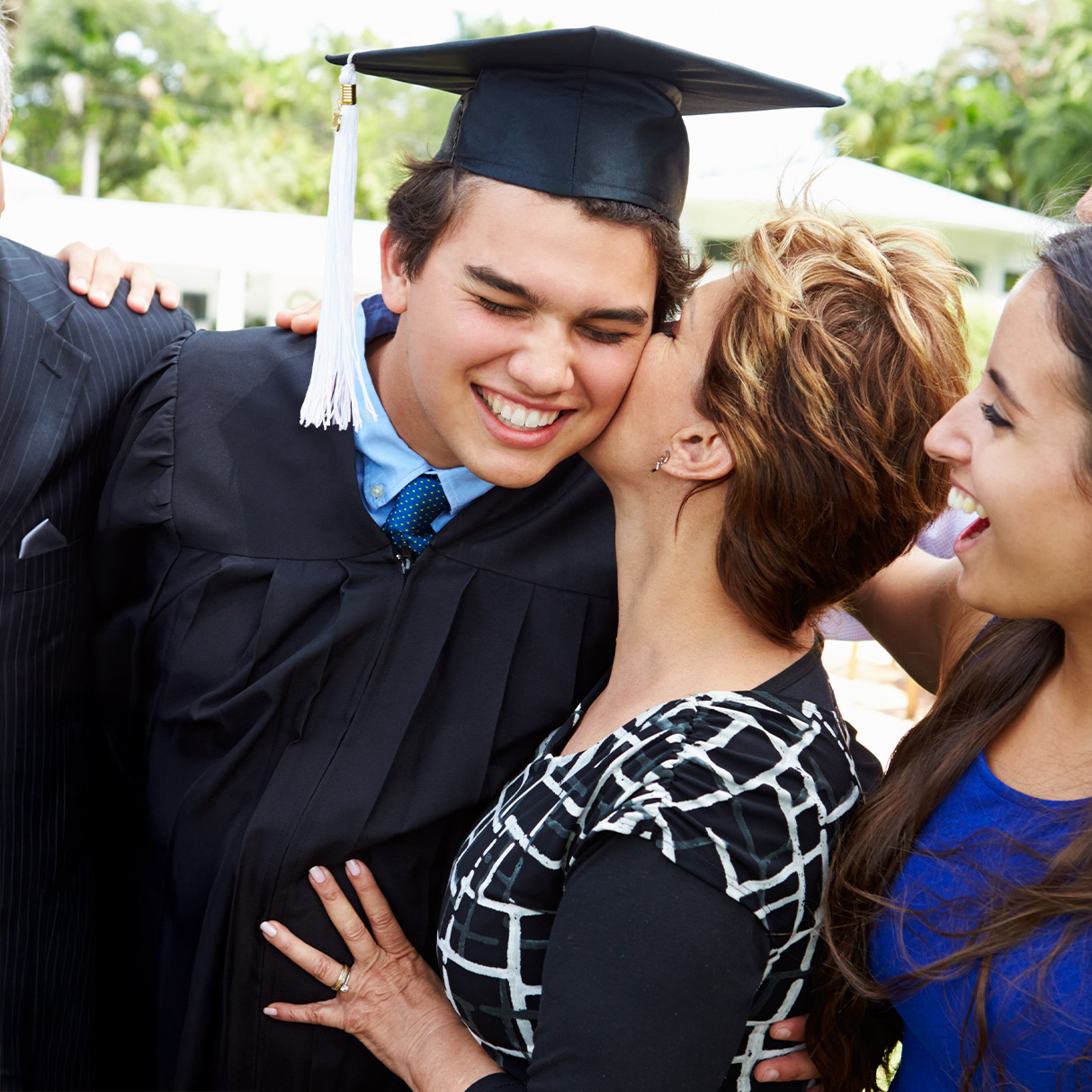 person in a graduation cap in gown with family